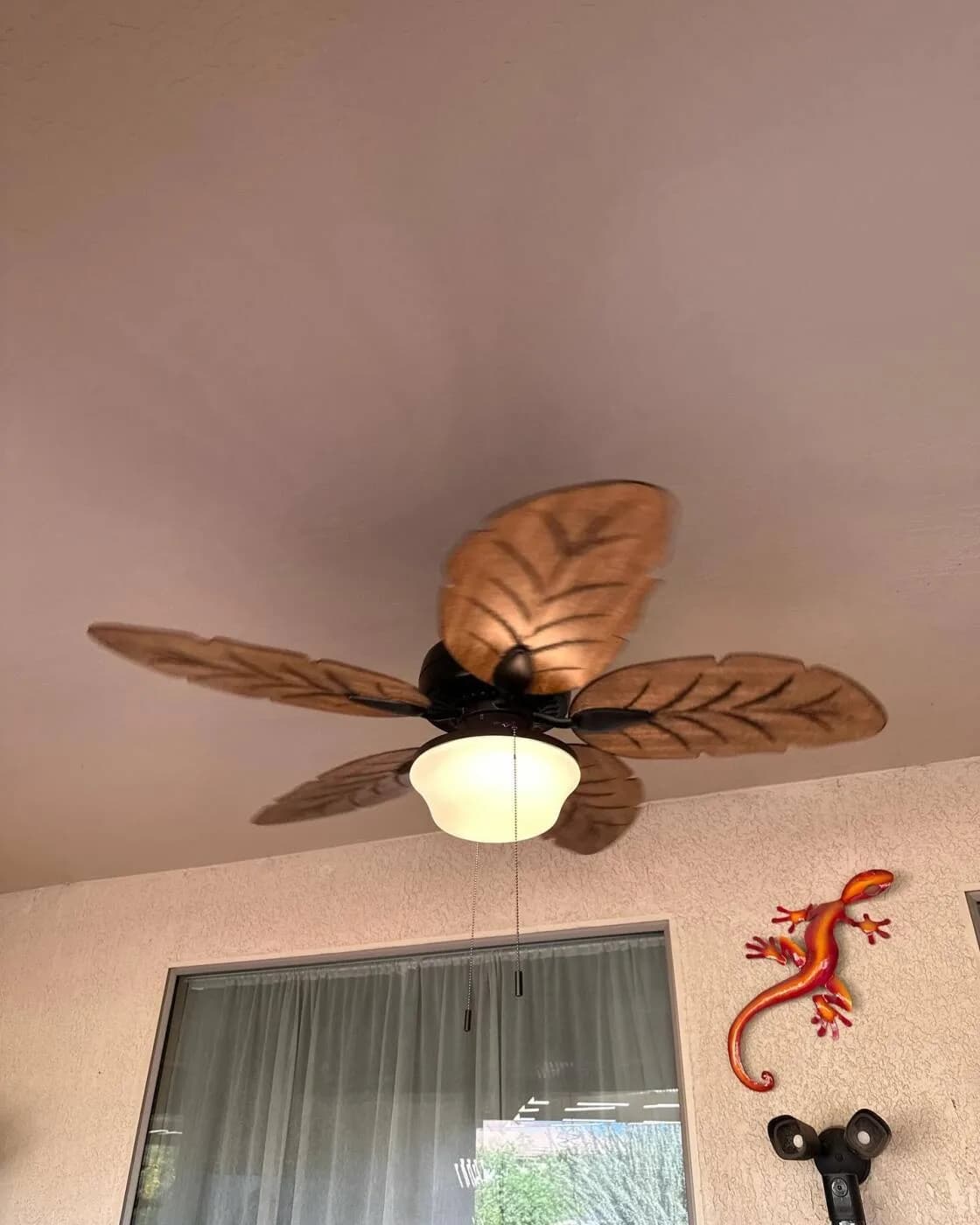 Outdoor ceiling fan with palm-leaf blades on a covered patio