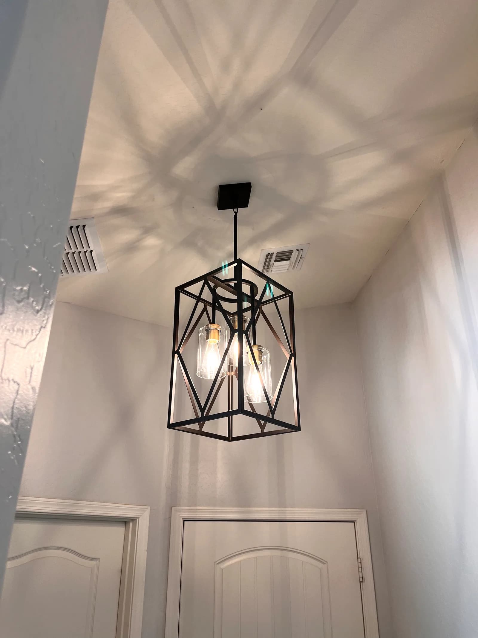 Black geometric cage lantern pendant with three Edison bulbs