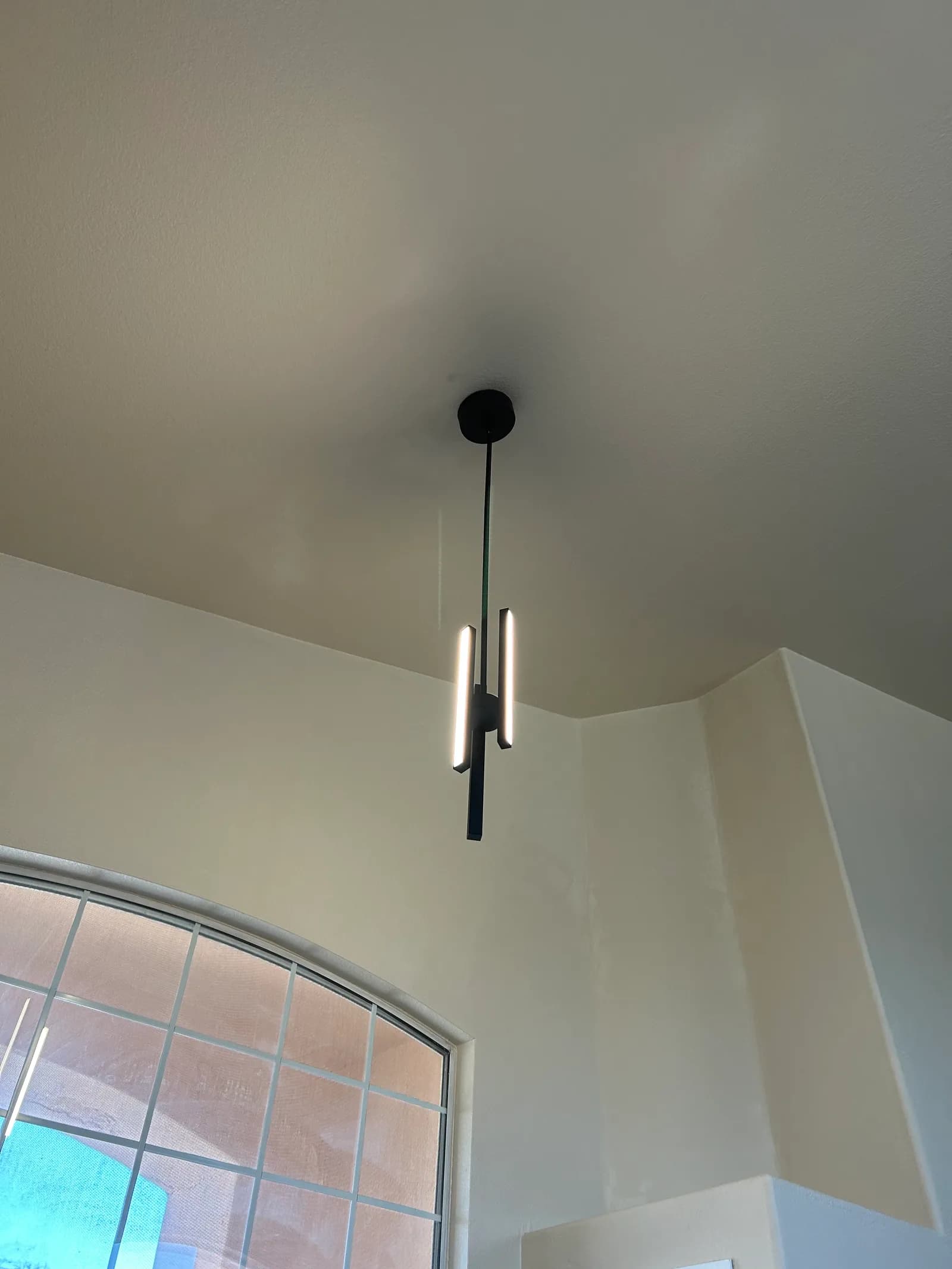 Modern black linear LED pendant hanging from a high ceiling